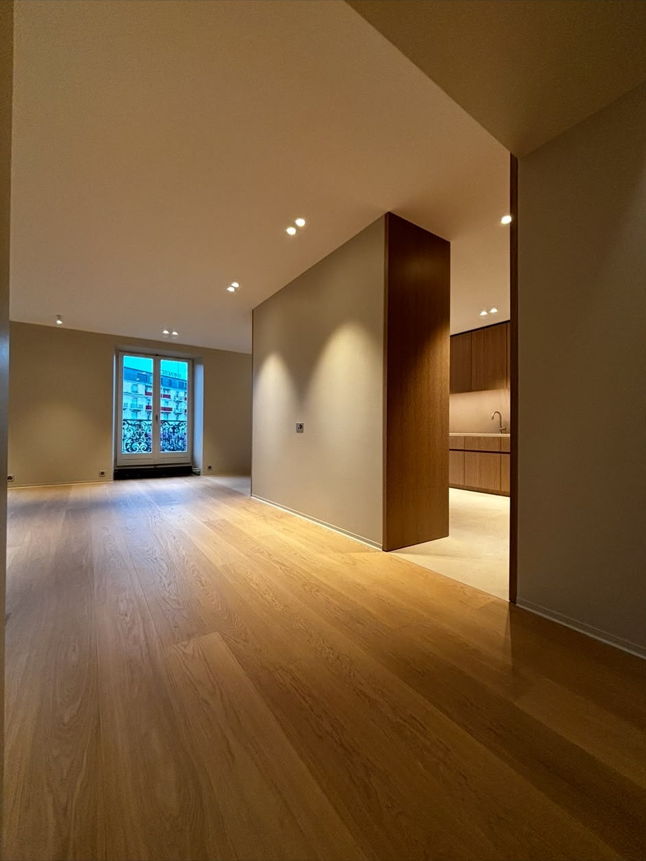Couloir d’appartement rénové : murs et plafond lisses peints, menuiseries en chêne, spots encastrés