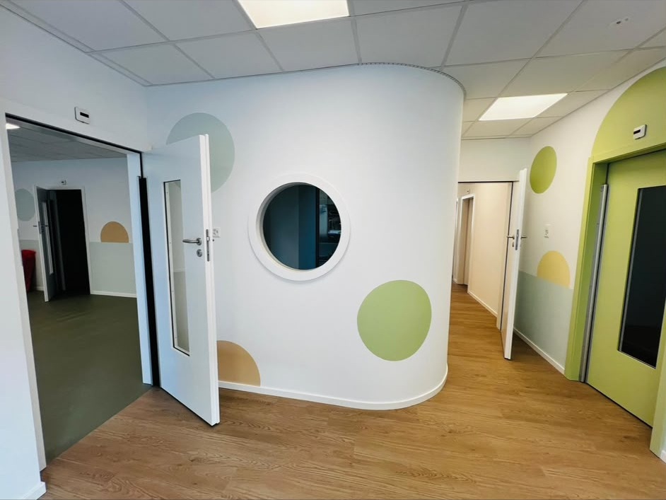 Crèche : paroi courbe peinte en blanc avec hublot et cercles de couleur peints au mur