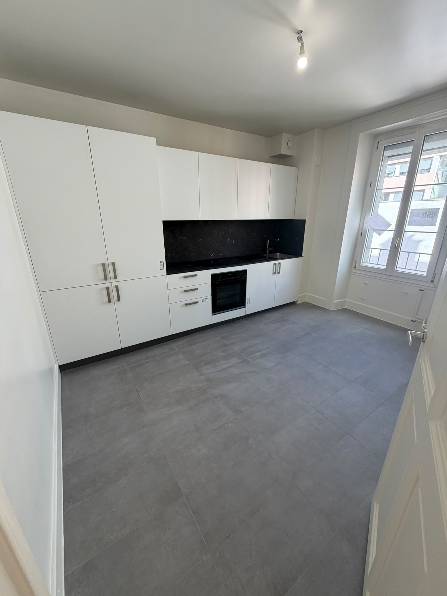 Cuisine repeinte en blanc, meubles blancs, crédence noire et carrelage gris
