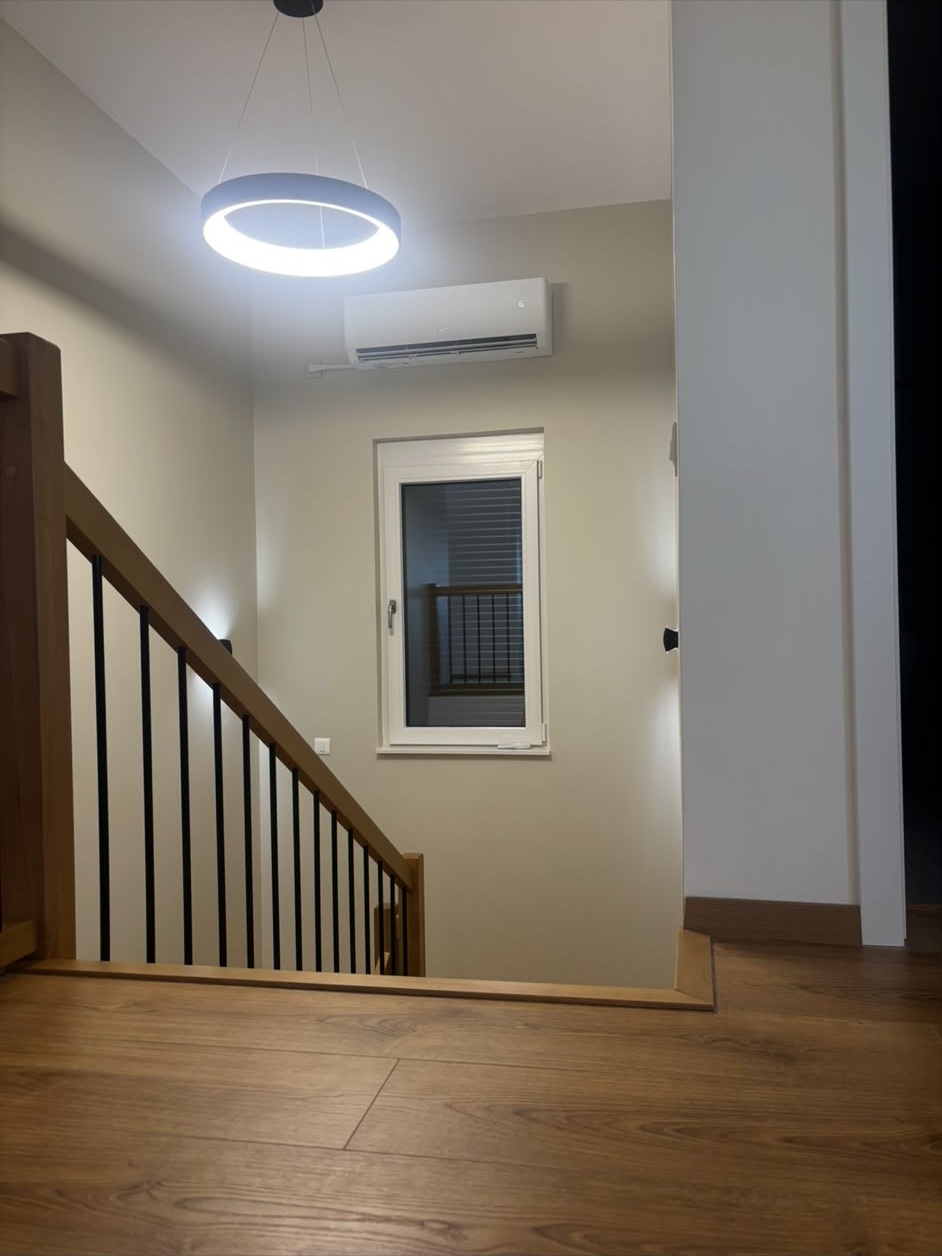Palier et cage d’escalier d’une maison peints en beige clair, garde-corps en bois et métal