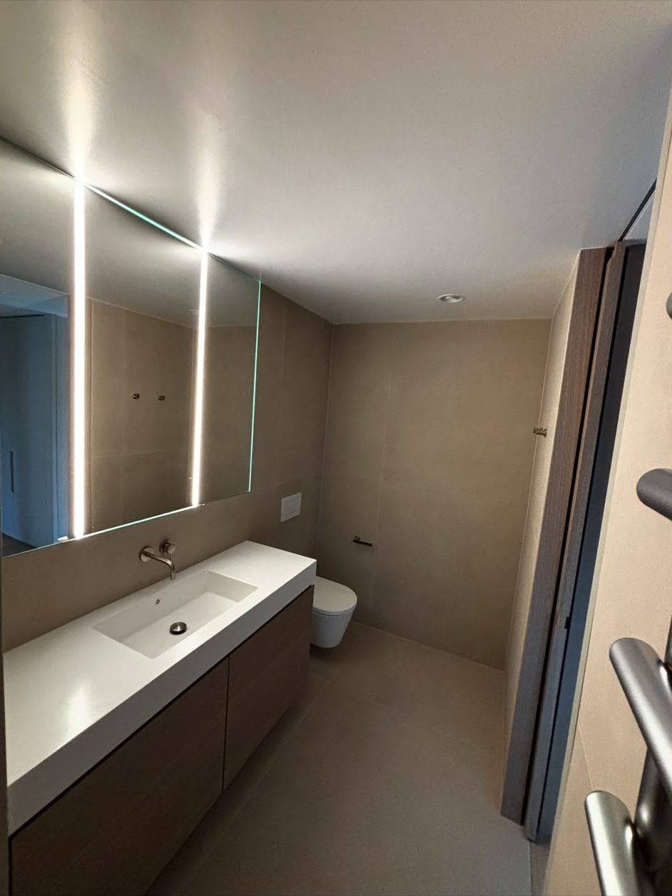 Salle de bains moderne : plafond peint en blanc, murs en grands carreaux beiges, miroir rétroéclairé
