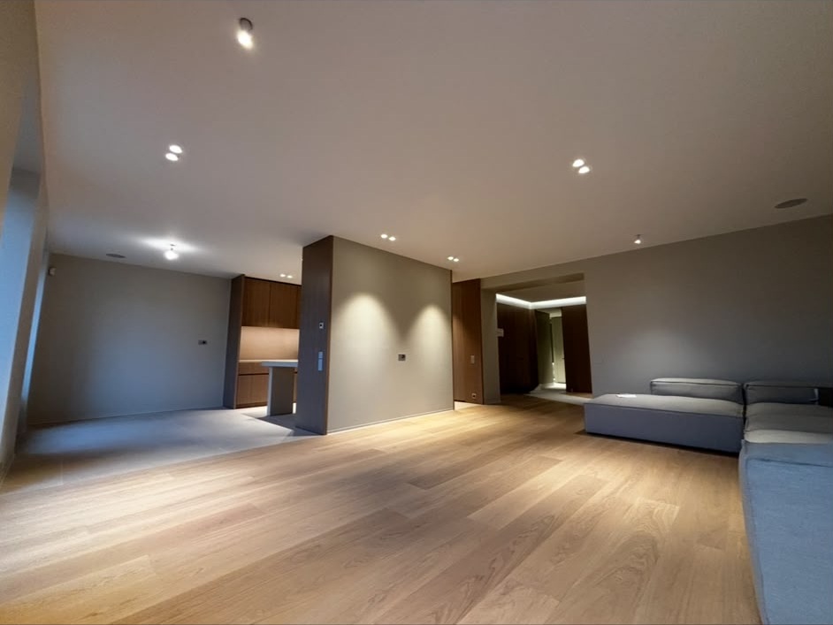 Grand séjour aux murs peints en gris clair et plafond blanc, parquet en chêne