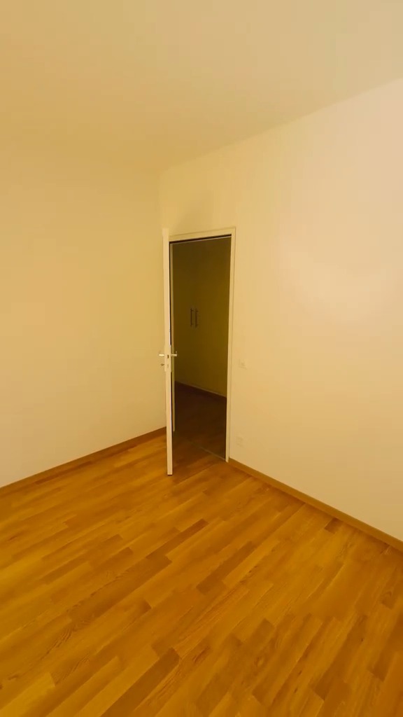 Grande pièce repeinte en blanc avec porte vers la pièce voisine, parquet en chêne