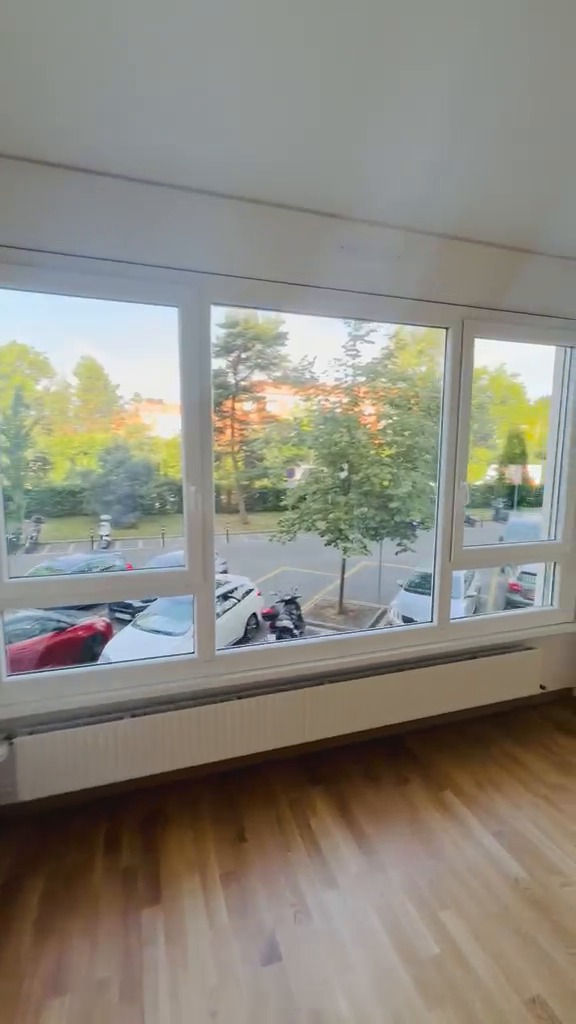 Séjour repeint en blanc avec grandes baies vitrées et parquet en chêne